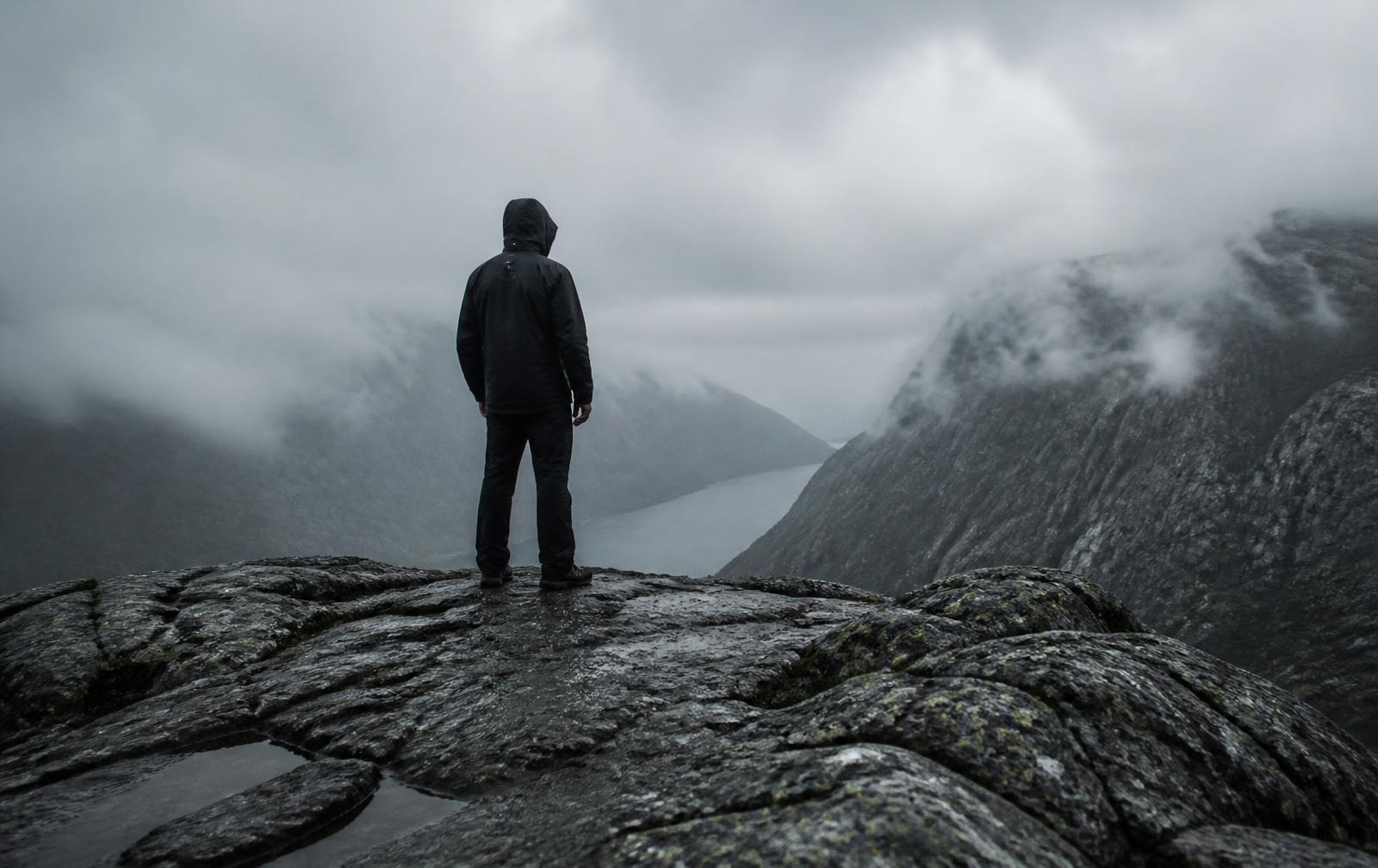 Figure in a black technical shell on a misted granite ridge